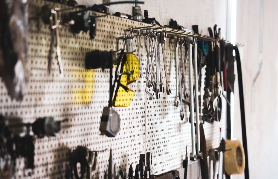 Lochwand mit verschiedenen Handwerkzeugen wie Maulschlüsseln und einer gelben Schutzbrille.