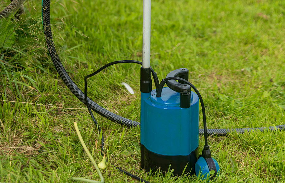 Regenfasspumpe mit gebogenem Bügel die auf der Wiese steht